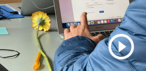 Mutacademy: Laptop mit Blume und Hand auf Tastatur